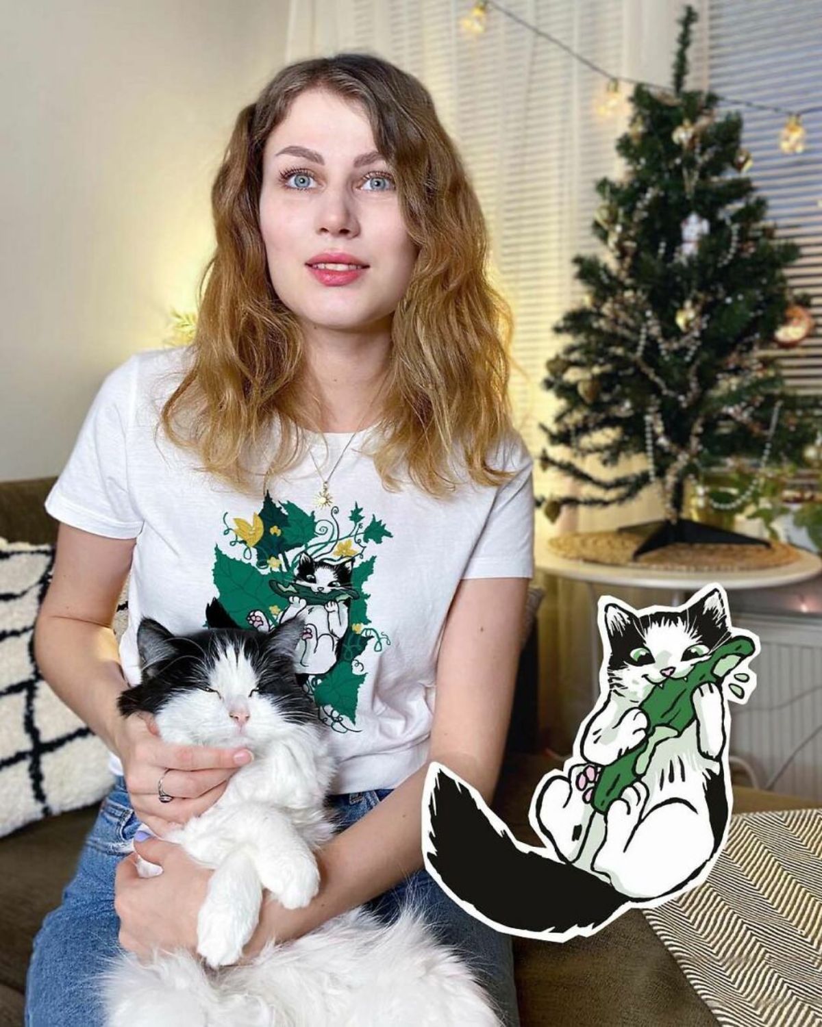 black and white fluffy cat on a woman's lap with a sticker of the cat eating a cucumber on the bottom right