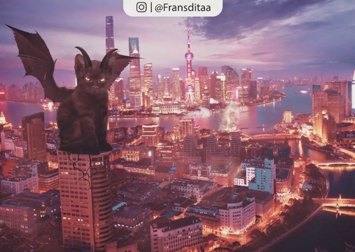 giant photoshopped black kitten with bat wings sitting on a tall building that's cracking