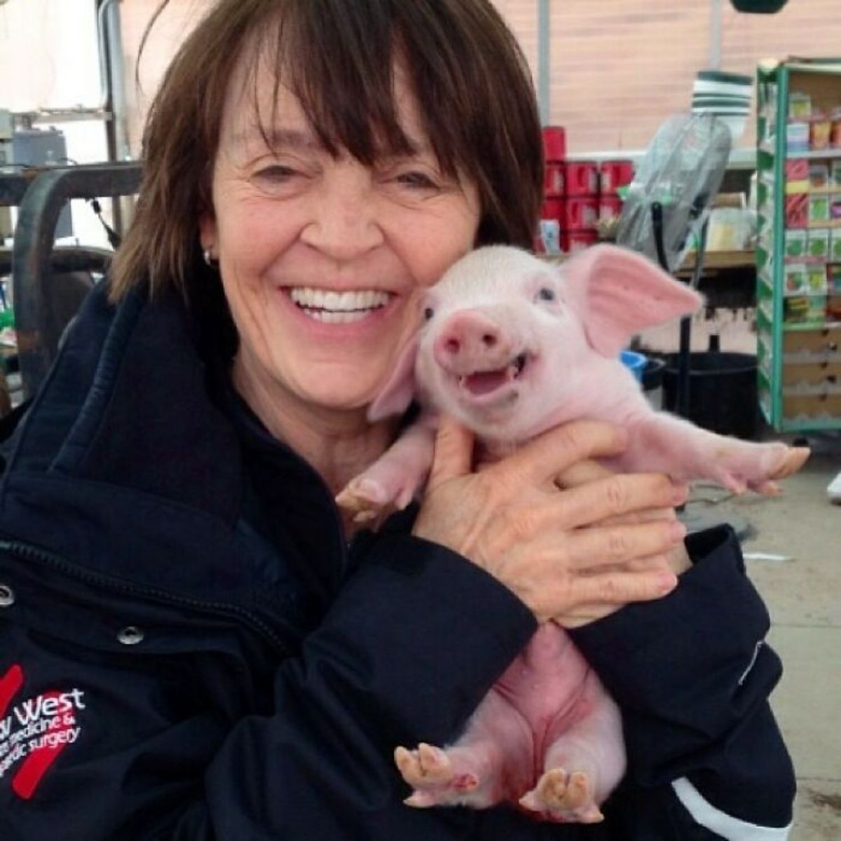 pink piglet with its mouth open being held by a woman